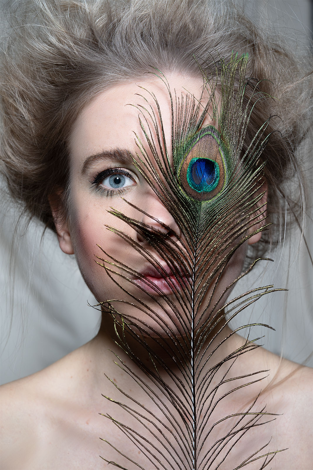 Künstlerisches Beauty-Editorial-Portrait einer Frau mit Pfauenfeder – fotografiert von Sternenschmiede – Visual Impact. Ausdrucksstarke Fine-Art-Fotografie mit Fokus auf Natürlichkeit, Textur und moderner Eleganz.