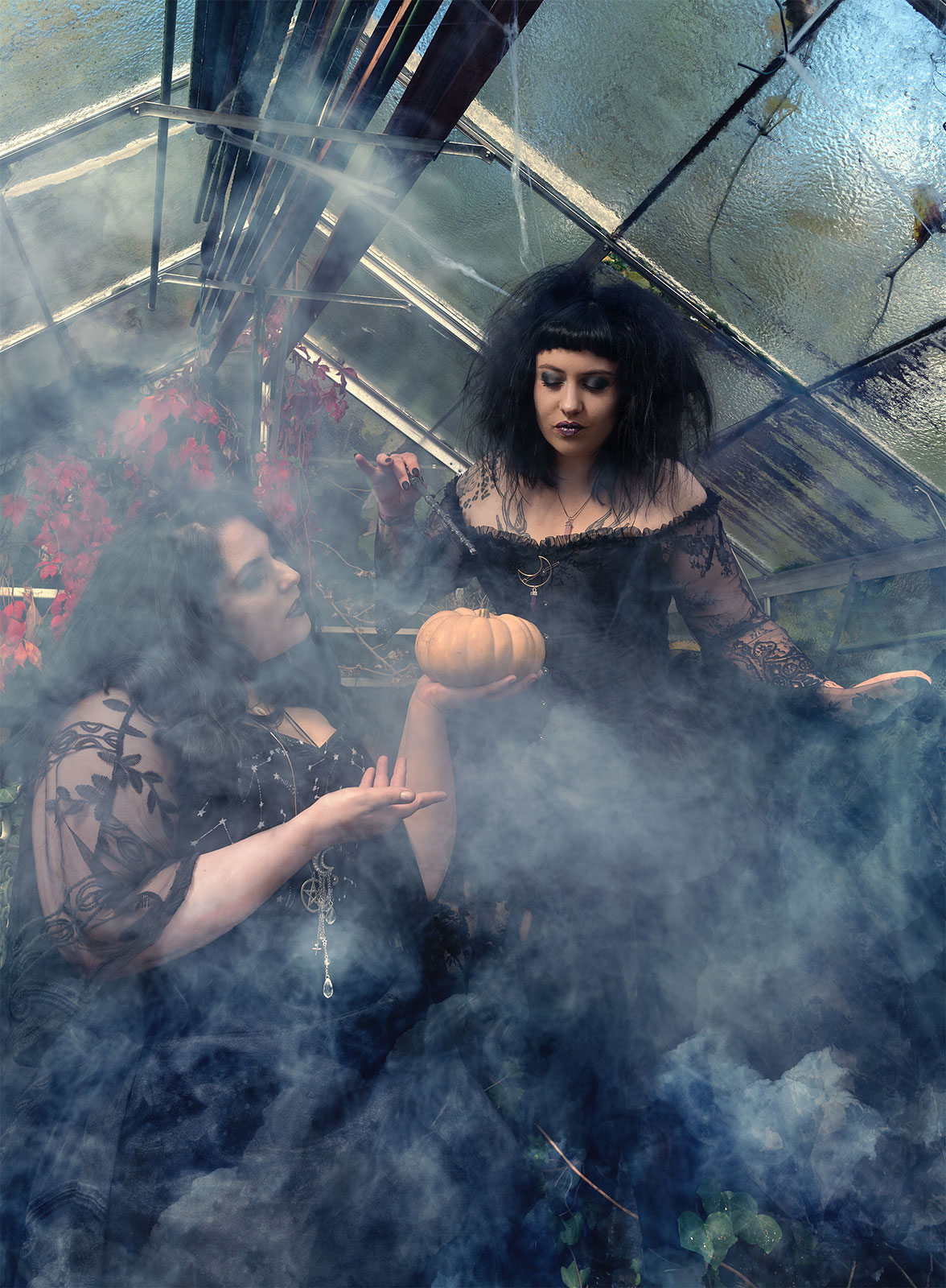 Gothic Fashion Editorial im Nebel eines Gewächshauses – zwei Frauen in dunkler Mode, umgeben von mystischer Atmosphäre und weichem Licht. Fotografiert von Sternenschmiede – Visual Impact.