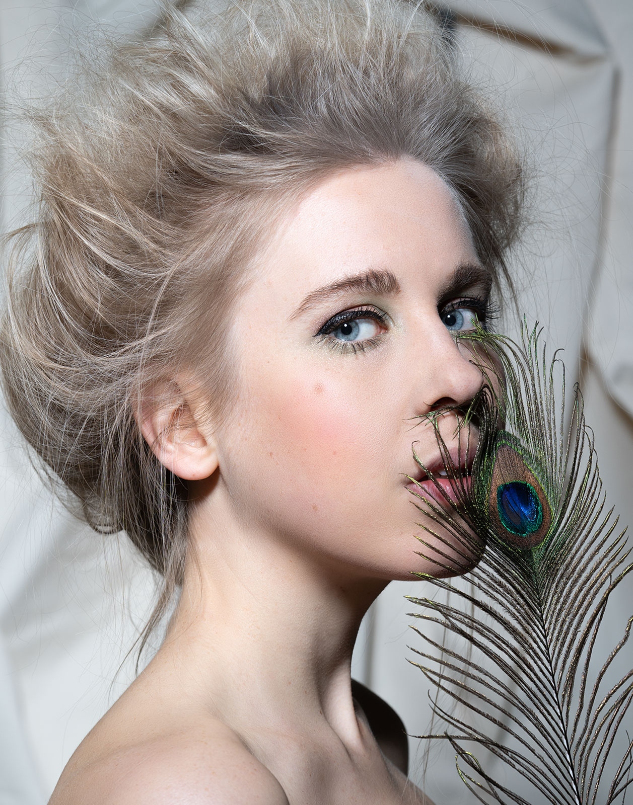 Cinematic Beauty Portrait einer Frau mit Pfauenfeder – natürliche Eleganz, Ausdrucksstärke und künstlerische Studiofotografie im Editorial-Stil.