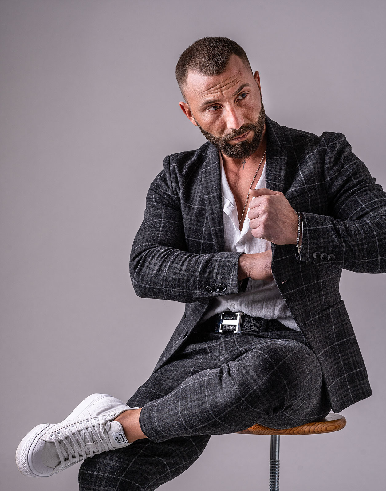 Charakterstarkes Cinematic-Fashion-Porträt eines Mannes im dunklen karierten Anzug – stilvoll, nachdenklich, selbstbewusst. Editorial-Fotografie mit filmischer Tiefe und moderner Lichtführung.